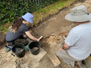 People excavate a ditch as part of an archaeological dig