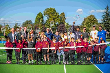 Cllrs, staff and children from Harmondsworth Primary stand at the net of a renovated tennis court in Harmondsworth Rec
