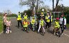 A group young children with their bikes and cycling instructors, wearing high-vis and helmets