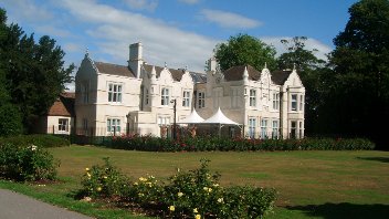 External view of Barra Hall main building with blue sky behind and flower beds in foreground